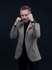 Portrait of a stylish elegant senior businessman with a beard and casual business clothes ready to fight hands gesture