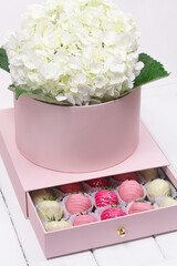 Pink Gift Flower Box with Chocolate Dipped Strawberries, on white wooden background.