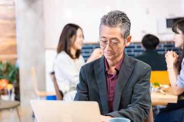Obraz premium カフェで仕事をする中年男性