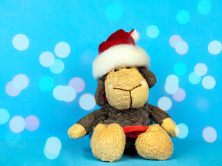New Year stuffed toy .lamb in a red cap .blue background and bokeh