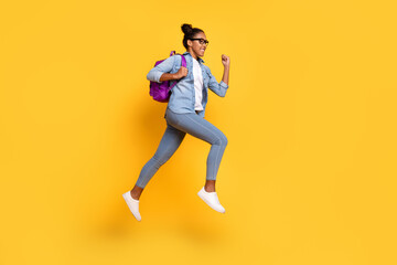 Fototapeta na wymiar Full size profile side photo of young african girl jumper active fast run rucksak college isolated over yellow color background