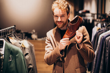 Fototapeta na wymiar Young handsome man choosing shoes at a shop
