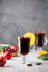 Glass of mulled wine surrounded by spices, orange blossom and branches of a Christmas tree. 