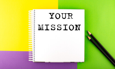 Minimal work space : sketchbook on the colorful background with YOUR MISSION text