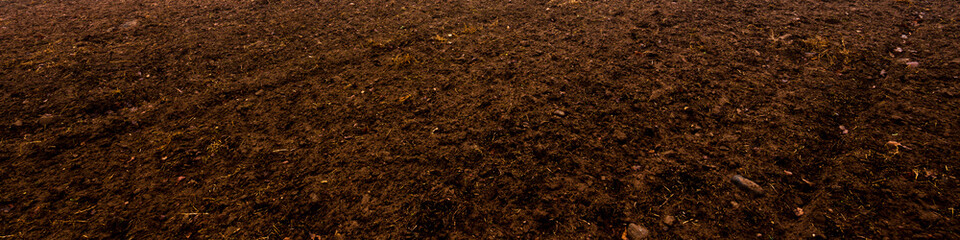 Plowed agricultural field, tractor tracks, soil texture close-up. Rural scene. Panoramic landscape....