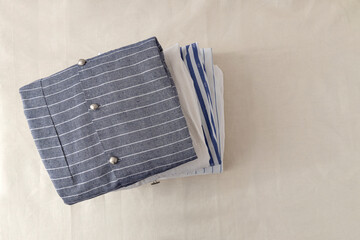 Top view of stack of natural cotton shirts on the white linen surface.Empty space