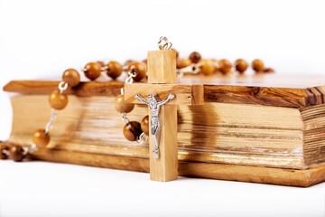 Bible with wooden cover and wooden rosary on white background.