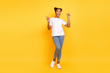 Full length photo of young pretty african woman indicate fingers empty space ad isolated over yellow color background