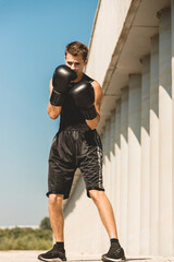 Fototapeta na wymiar Man exercising and fighting in outside, boxer in gloves. male boxer portrait