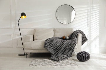 Soft chunky knit blanket on sofa in living room. Interior design