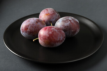 fresh plums in a black plate