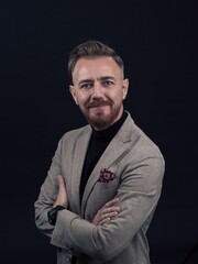 Portrait of a stylish elegant senior businessman with a beard and casual business clothes in photo studio isolated on dark background gesturing with hands