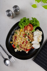 a cooked spicy asian fried rice stir fry with beef , slice fresh red tomato, fresh green lettuce and white crackers in black oval plate with dark blue napkin with white line