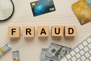 Flat lay composition with word Fraud on white wooden table