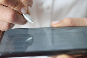 Man put signature on digital tablet device, open document and space for signing