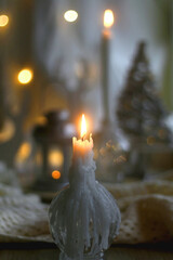 Candle holder with lit candle, reindeer and Christmas tree figurines and soft blanket. Hygge at home. Selective focus.