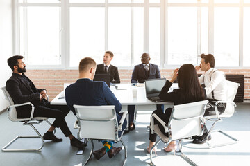 Group of young business people working and communicating while sitting at the office desk together with colleagues sitting. business meeting