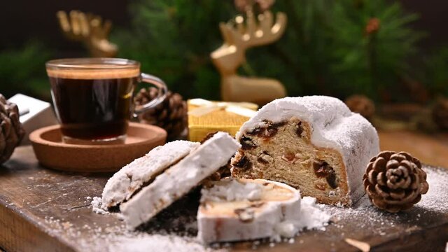 Stollen. Traditional German sweet bread with dried fruits and marzipan for Christmas. Aromatic espresso coffee near the Christmas tree and sweets. Distance movement in the frame