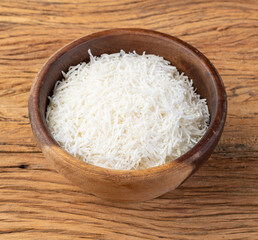 Grated coconut flakes in a bowl over wooden table