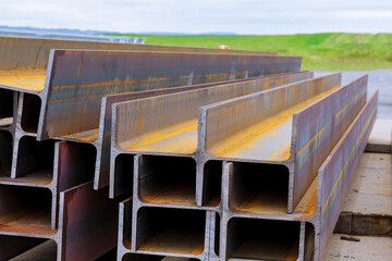 The stack of rolled metal is on the background of a green field, facing the steel profile.