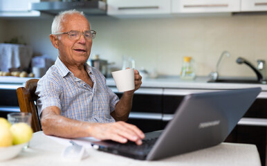 Old man learning to use laptop at home