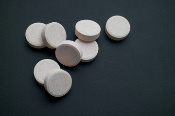 vitamins, tablets and pills lie on a black background. medicines are on the table. pills on a black...