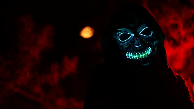 terrifying glowing skull mask on human in darkness, Halloween costume