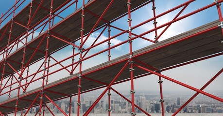 Construction scaffolding over a cityscape against clouds in the blue sky