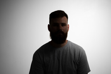 Close-up portrait of a handsome a brunette brutal bearded man in a grey t-shirt. Stylish and handsome man with a beard.