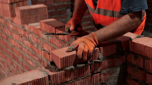 The builder is laying the bricks. The process of building a brick wall