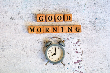 Good morning text on wooden cubes and alarm clock on gray texture background