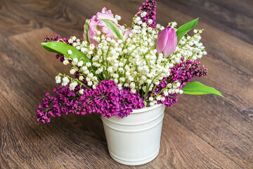 Lily of the Valley and Lilac Bouquet in Vase on Wooden  Background with copy space  .Spring Flowers Background