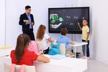 Teacher and pupil using interactive board in classroom during lesson