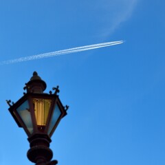 contrail of an airplane in the blue sky and a lantern