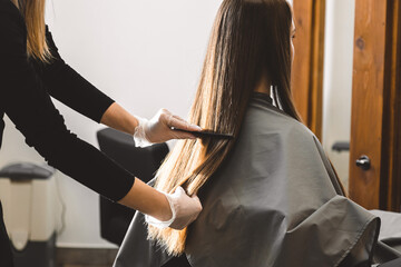 Master hairdresser combs the girl's hair after washing and before styling in a beauty salon.