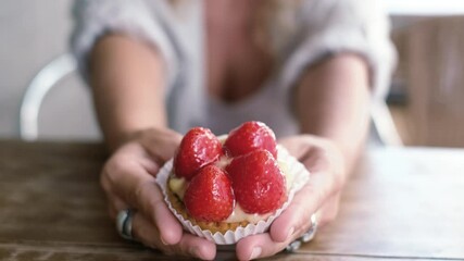 Close up of woman hands showing and holding a tasty natural strawberry bakery little cake at the cafe. Concept of snack and morning healthy breakfast for people. Diet and happy sugar food lifestyle
