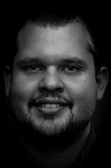 Fototapeta premium Extreme closeup in black and white of a young latin man with bright eyes, beard and short hair
