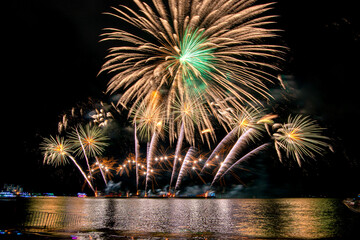 Amazing beautiful colorful fireworks display on celebration night, showing on the sea beach with multi color of reflection on water	