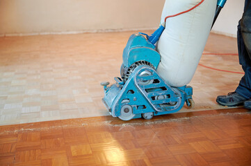 Hardwood floor restoring - Worker polishing parquet floor with grinding machine