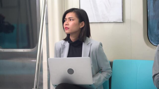 young asian woman passenger  using laptop computer sitting in subway . problem in Public Transport in city lifestyle . broken subway