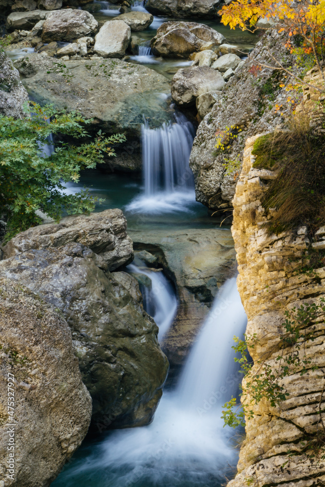 Sticker Vertical shot of a babbling waterfall in rocks