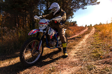Enduro motorcyclist on trail in autumn forest