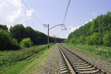 railway line in the summer forest, blue sky