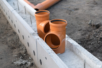 Sewer Pipe corner on the construction site. New Orange PVC plastic Drainage pipe Tube