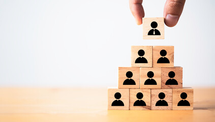 Hand putting manager icon on top of wooden stacking of staff icons for promotion leadership and...