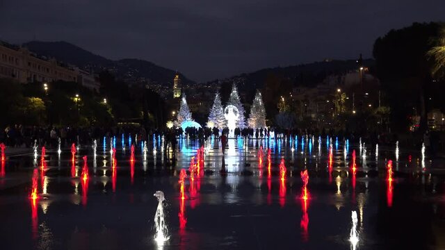 People attend Christmas decorations and coloured water fountains in Nice, France