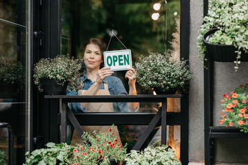 Small business owner smiling while turning sign for reopening of place after quarantine due to covid-19