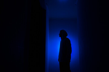 Silhouette of a guy in the dark.
Man in blue light.