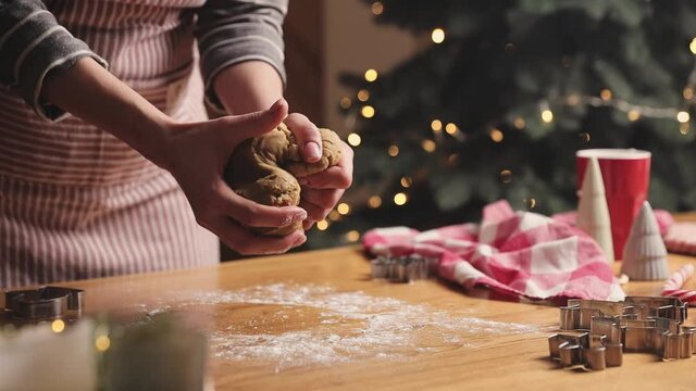 Merry Christmas, Happy New Year. Gingerbread cooking, cake, biscuit or strudel baking. Woman in apron is kneading, massaging dough. Girl gently holding, creases dough. Christmas decorations at kitchen