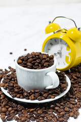 cup with coffee beans and an alarm clock, conceptual photography on white background, vertical